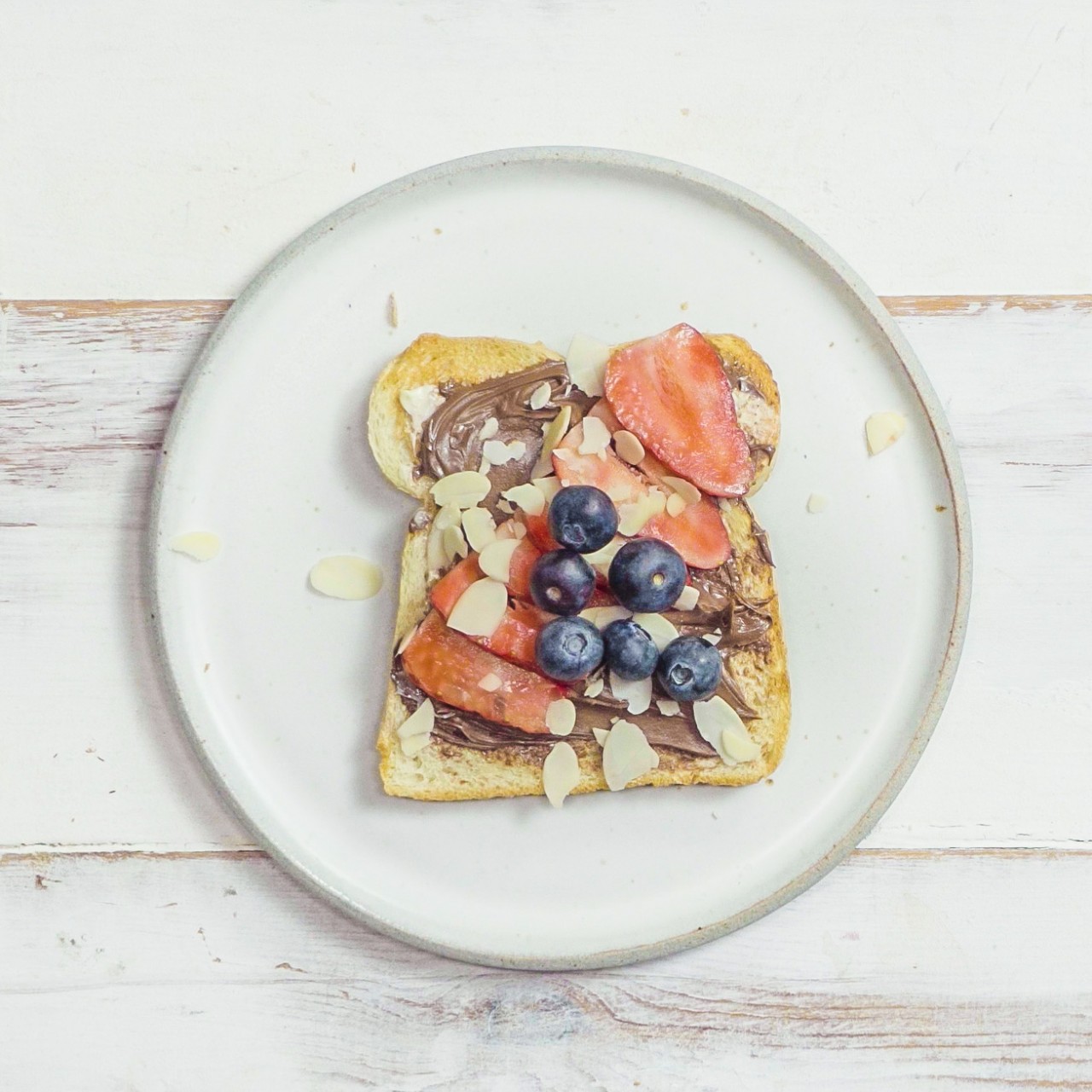  Nuss-Nougat-Creme Toast Deluxe mit frischen Beeren und Mandelblättchen